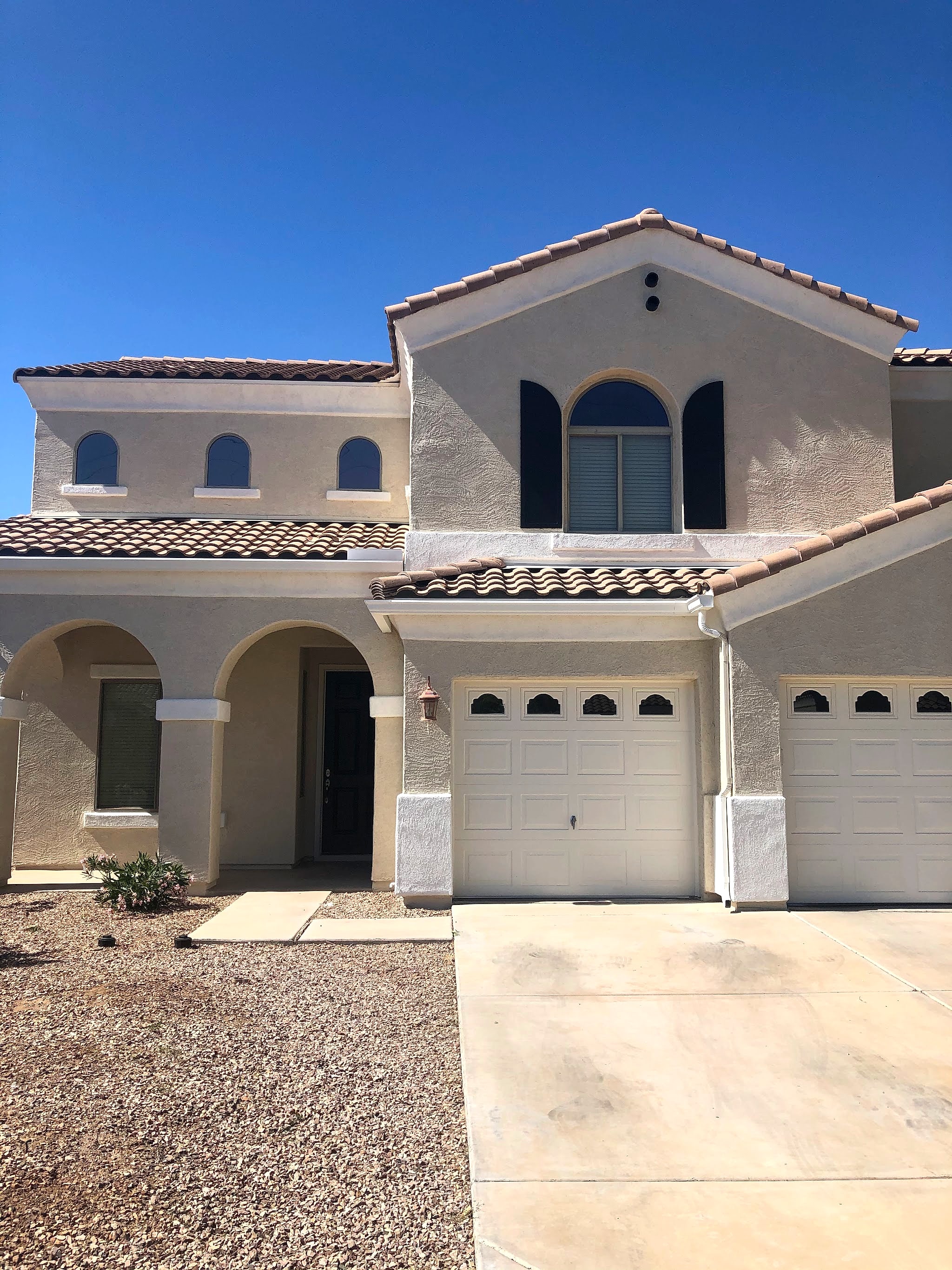 Two-story stucco home with a tile roof, freshly painted