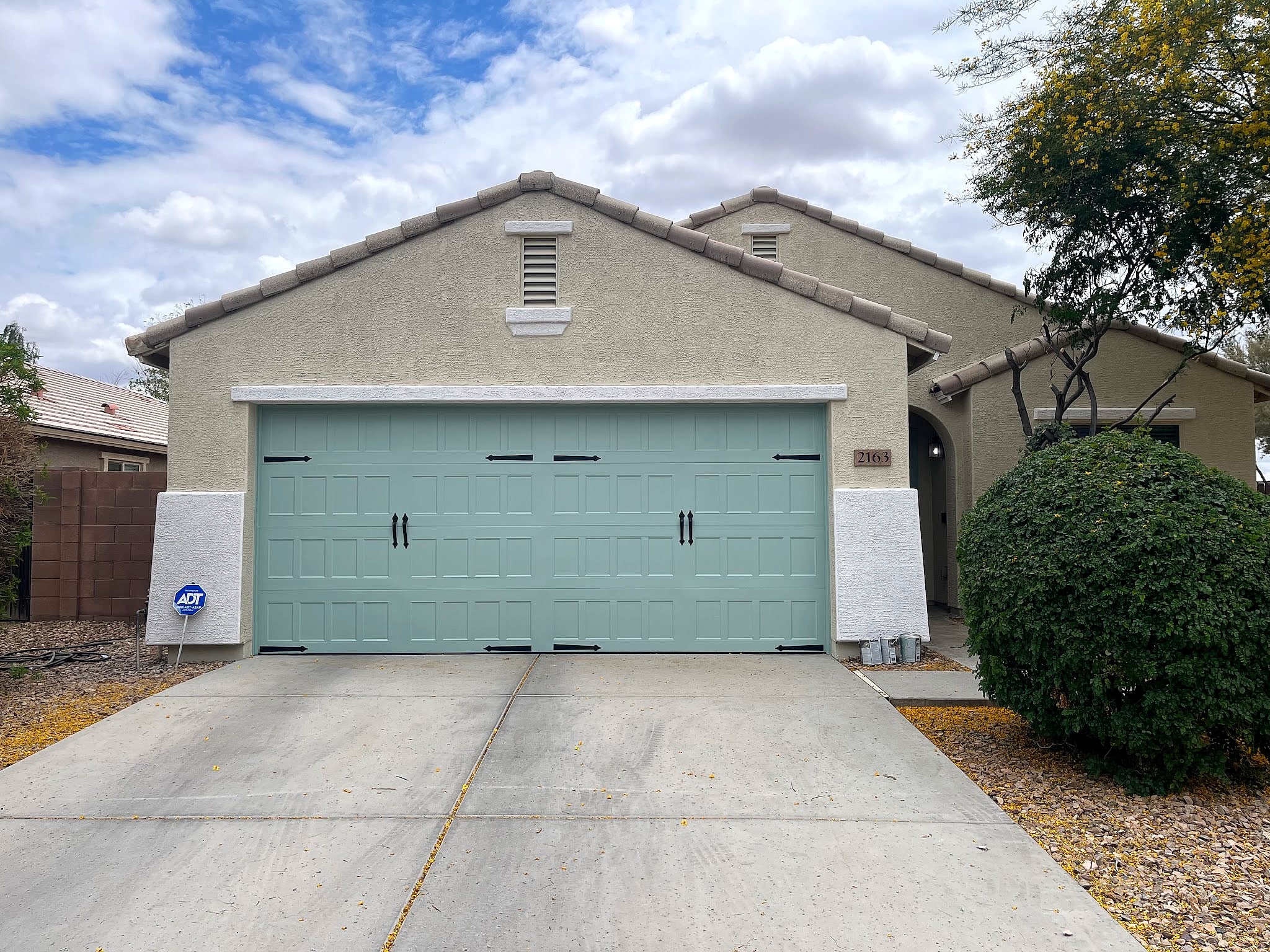 Sage green garage door on a greige stucco house
