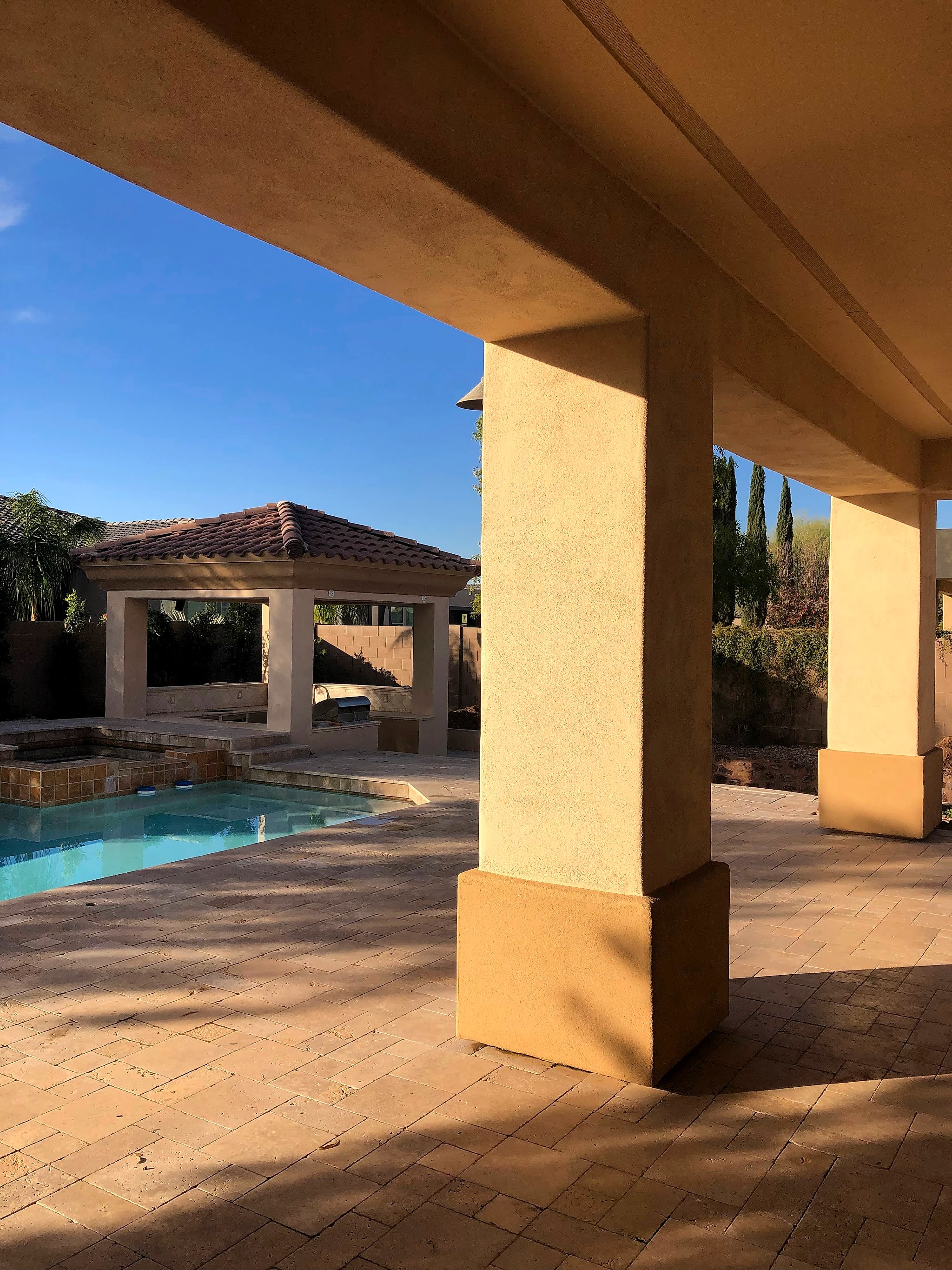 Backyard patio columns and ramada by a pool, freshly painted