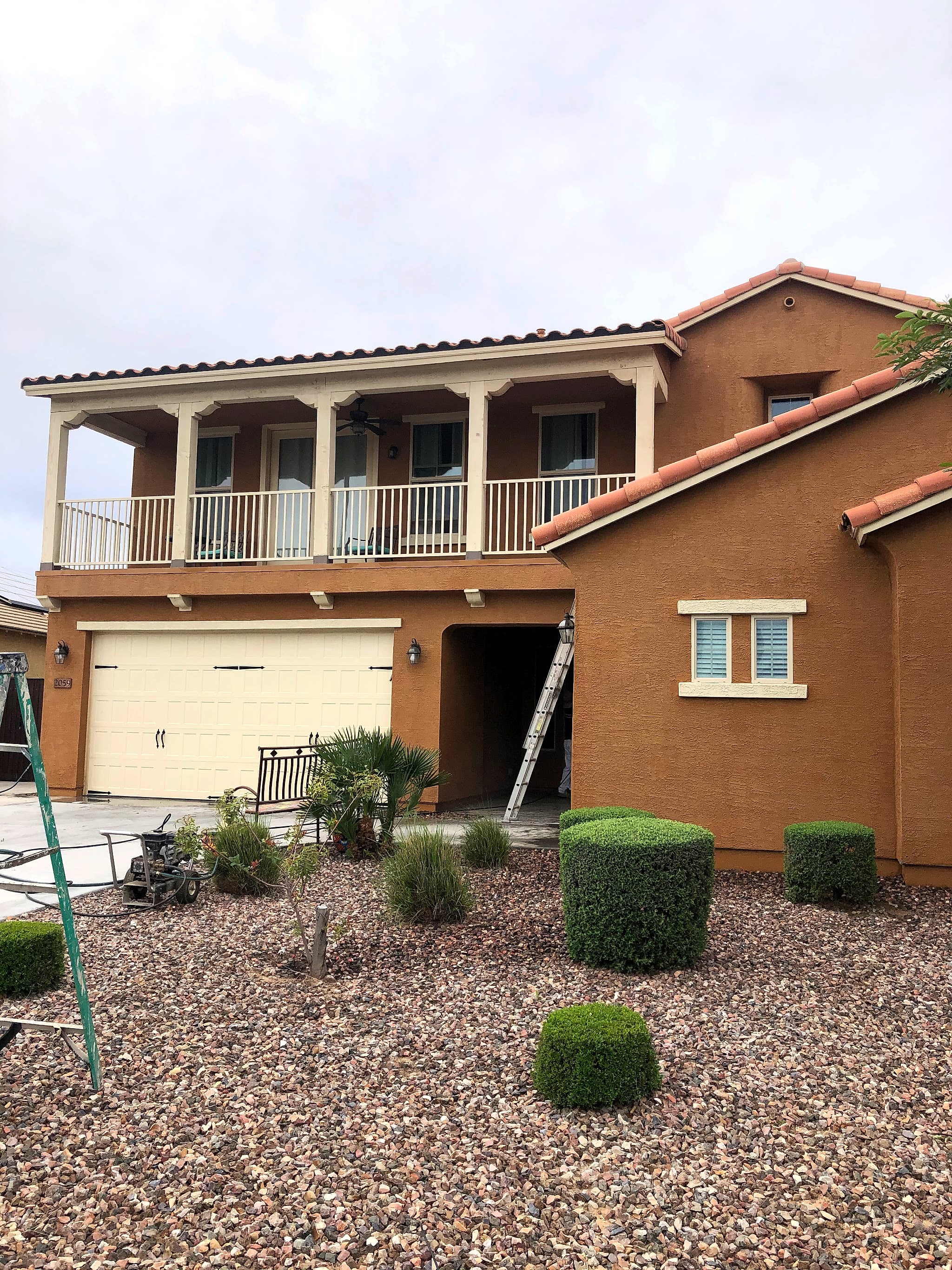 Two-story brown stucco home with a balcony, ladder still up