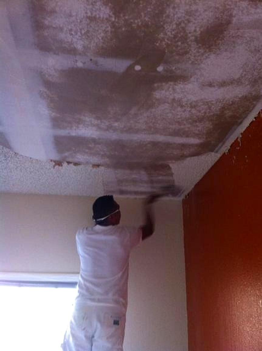 Painter spraying a ceiling with the room covered