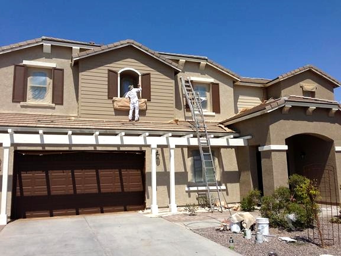 Painter on a ladder at an upstairs window during an exterior job